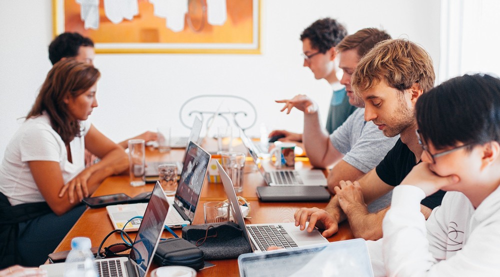 Group of young people on laptops working at a small startup business with a 1300 number