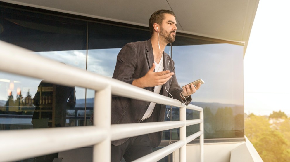 Businessman on a balcony using his mobile phone with a 1300 number