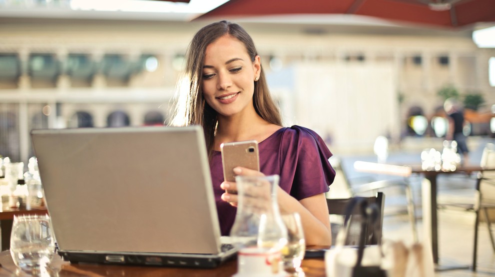 Young businesswoman at a cafe with a laptop on her 1300 number mobile phone