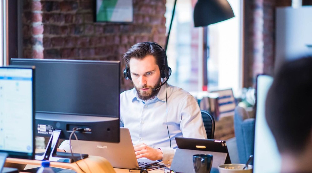 Businessman in an office with a headset researching 1300 number providers