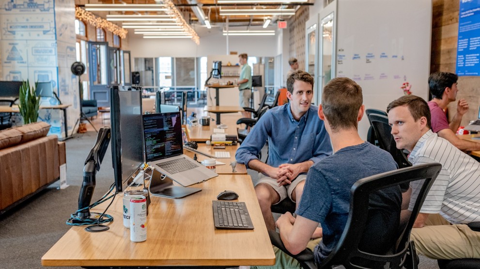 Office workers discussing getting a 1800 number sitting around a laptop