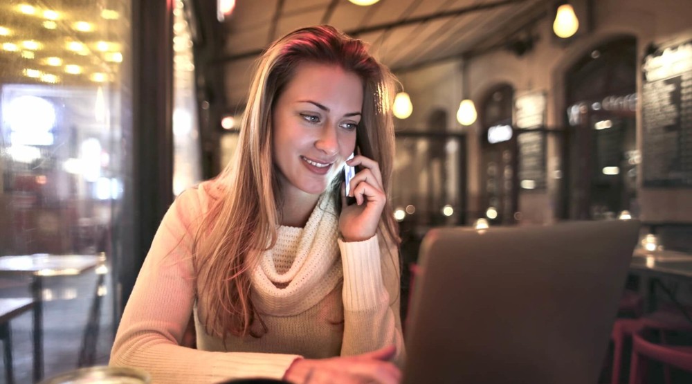 Young businesswoman working from a cafe on her mobile phone with a 1300 number