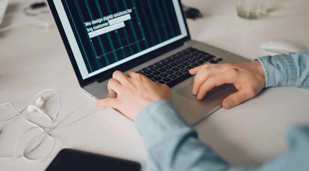 Close-up of man in shirtsleeves working on his business laptop designing business 1300 phone number Smartnumber solutions