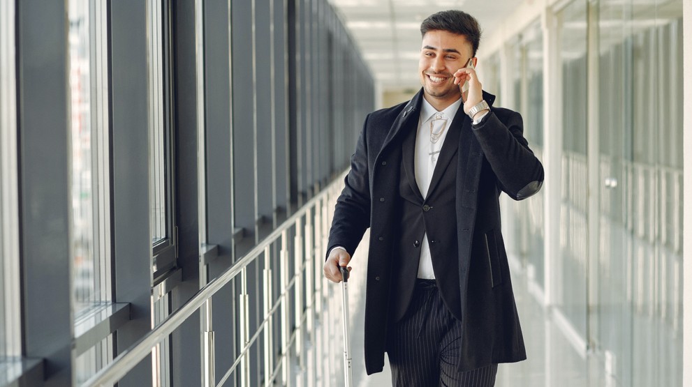 Businessman taking a 1300 number call on his mobile with luggage