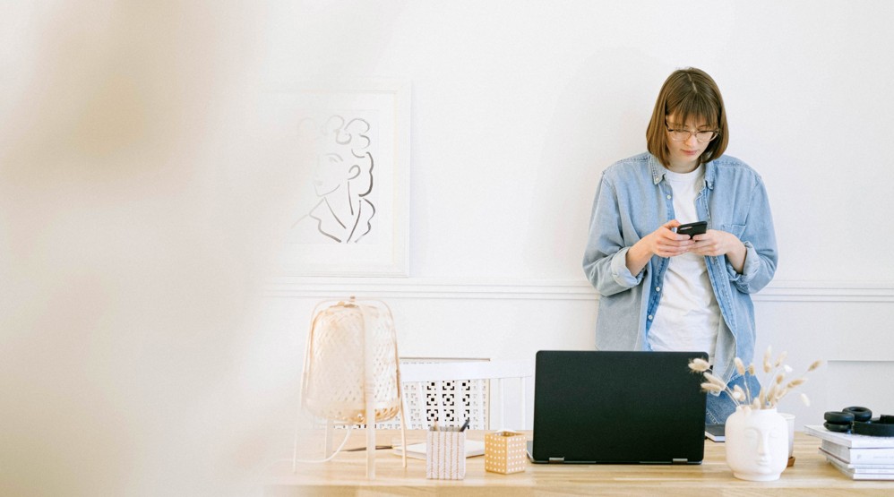 Female entrepreneur artist at desk with laptop and dialing a 1300 number