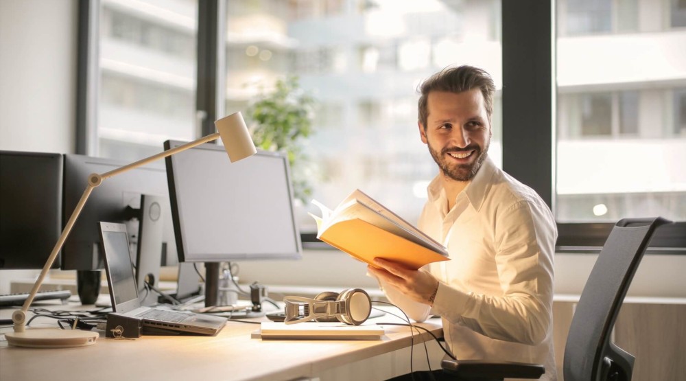 Smiling young businessman at his desk reviewing 1800 number costs